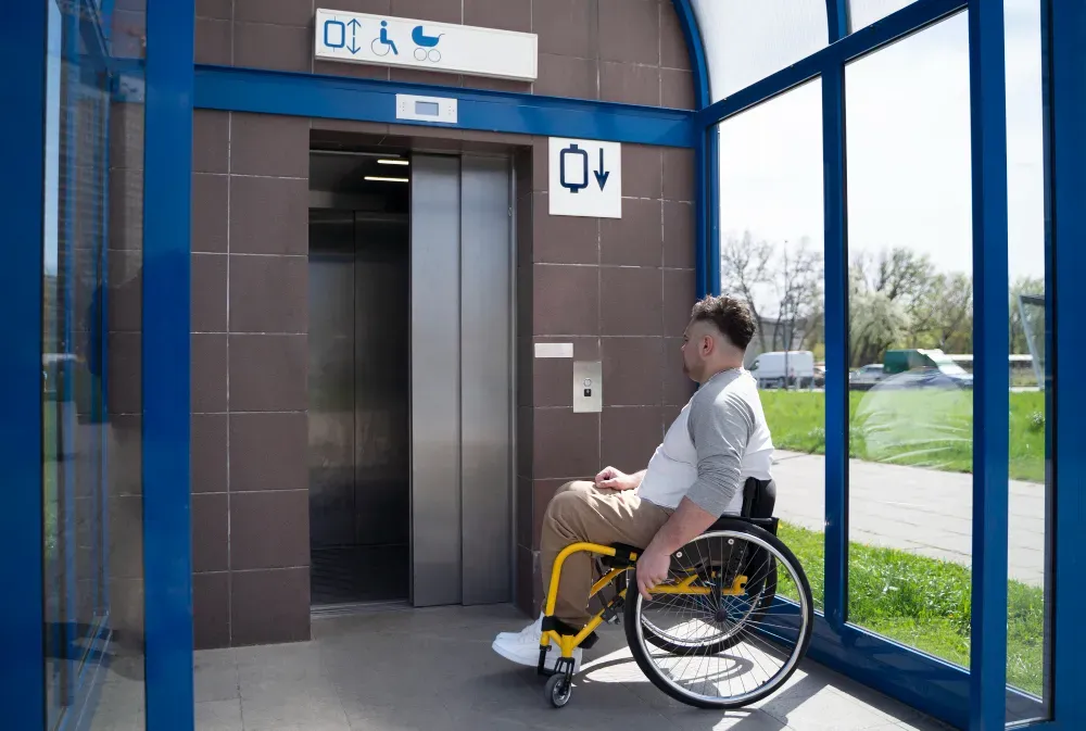 A resident using a wheelchair waiting at a communal lift in a block of flats