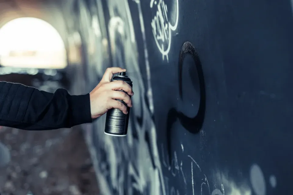 Graffiti being sprayed on an underpass wall