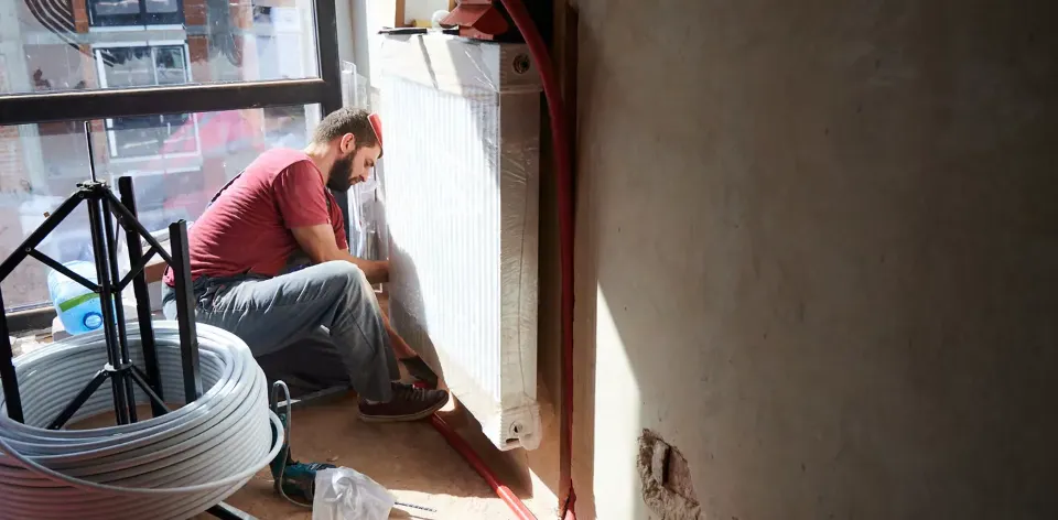 An operative repairing a radiator in an occupier’s home