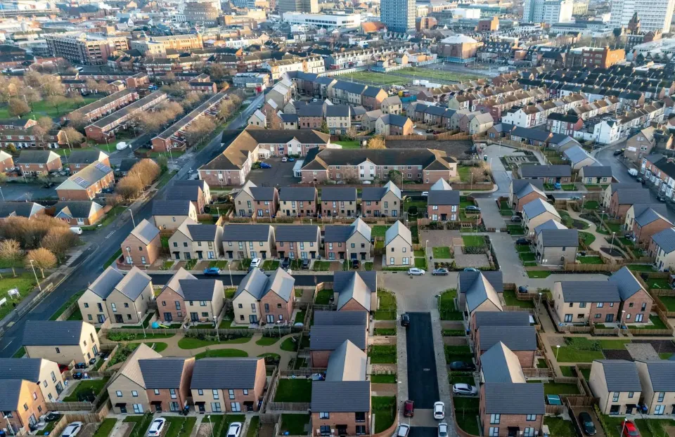Aerial view of a housing estate with rows of homes and tree-lined streets