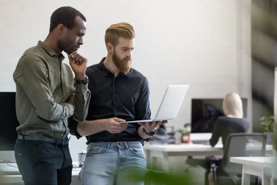 Two colleagues reviewing work on a laptop