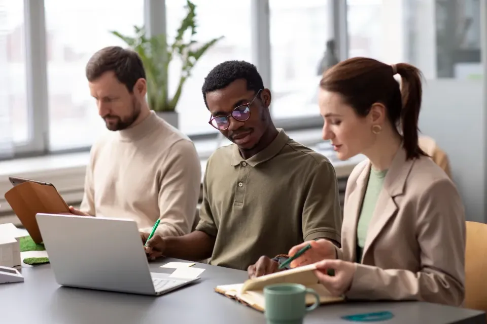 Three colleagues working around a laptop