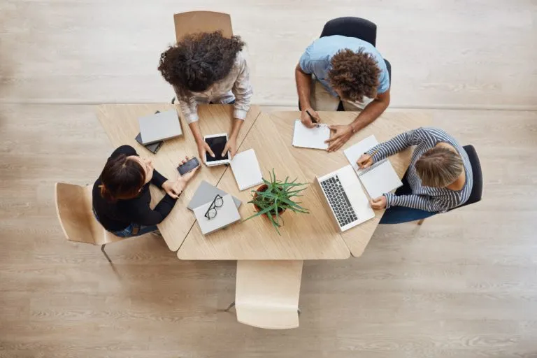 Neo Technology startup team collaborating in a coworking space, discussing future digital projects using a laptop and tablet.