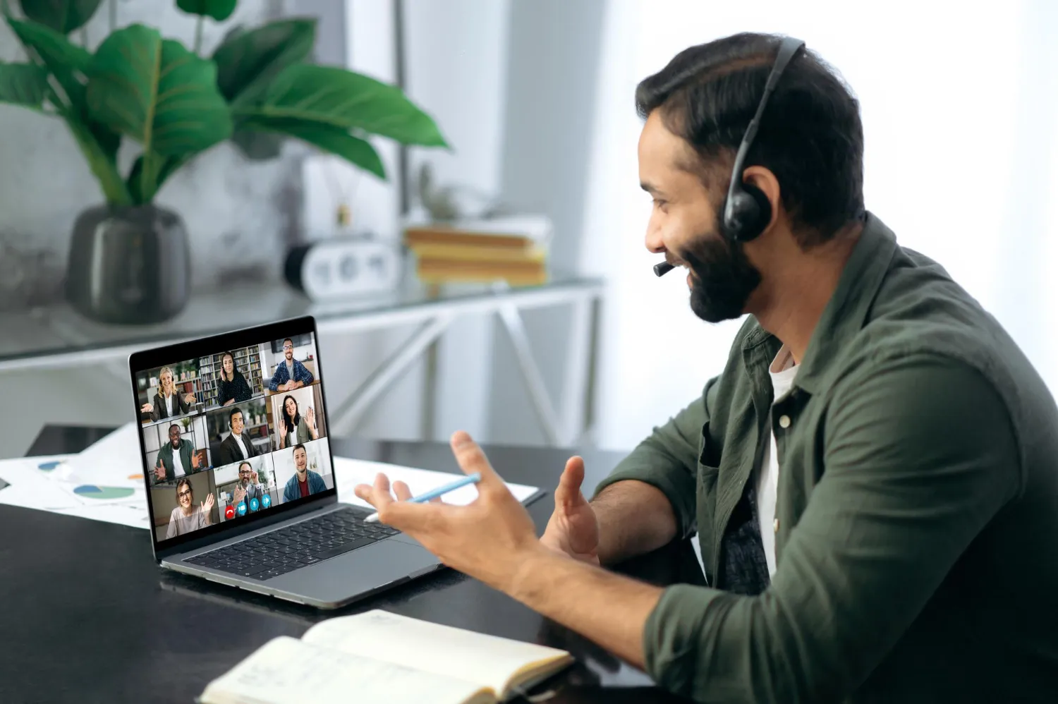 successful busy mixed race successful man-sitting work desk modern office using laptop talking multiracial business team via video conference virtual online meeting remote negotiations
